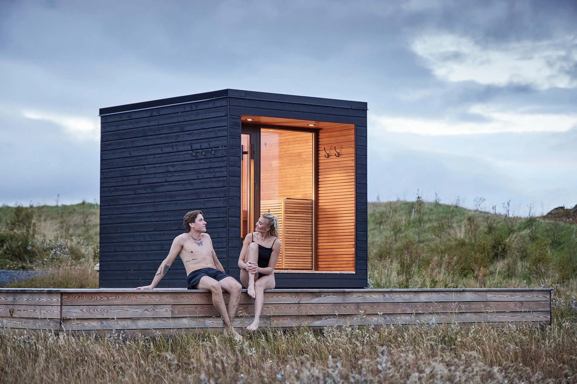 Dark-clad Arti outdoor sauna with a glazed entrance on a timber deck