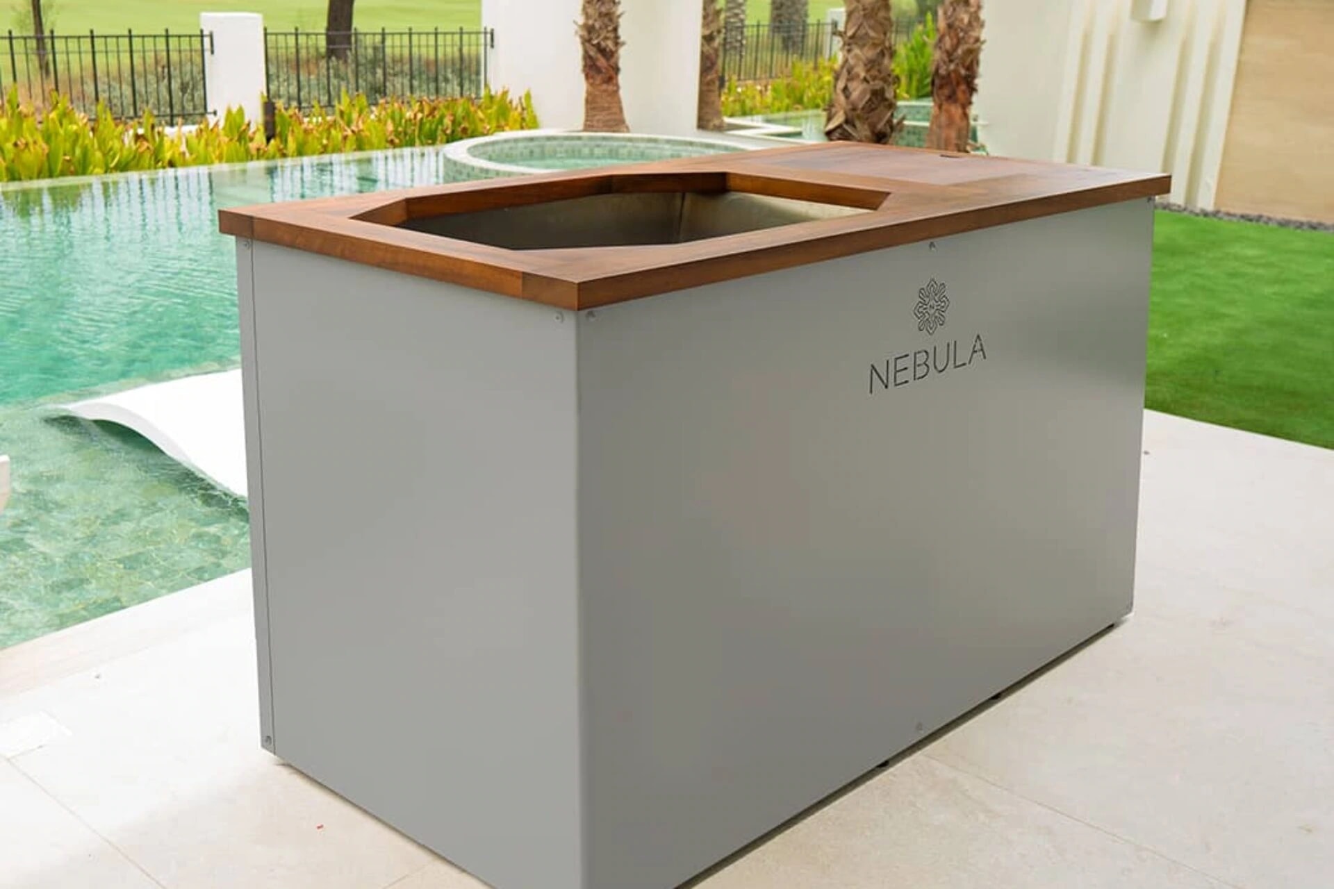 Pure Plunge by Nebula in grey with a teak surround and stainless steel interior beside a pool
