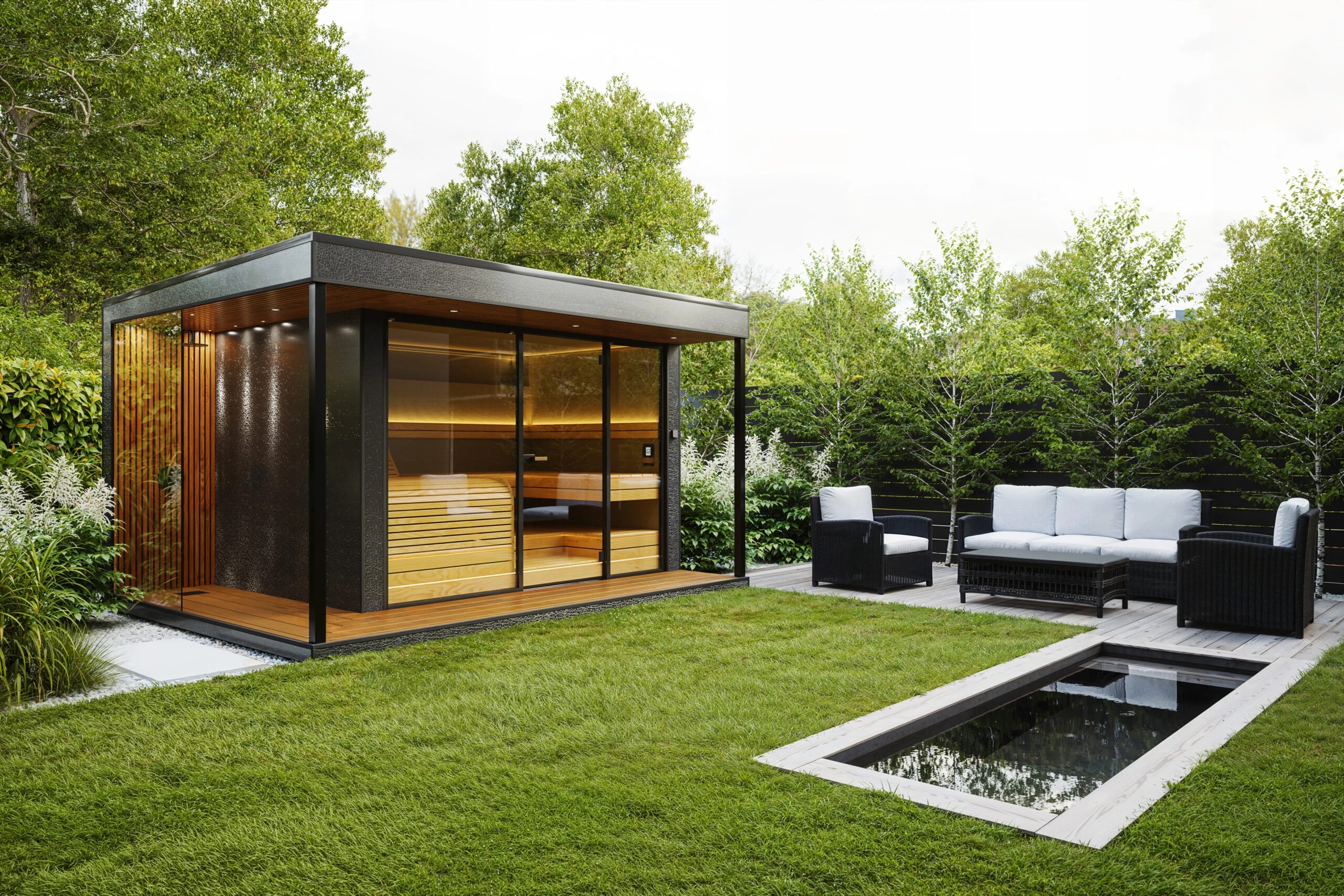 Quu sauna with panoramic glass walls and warm timber interior in a landscaped garden