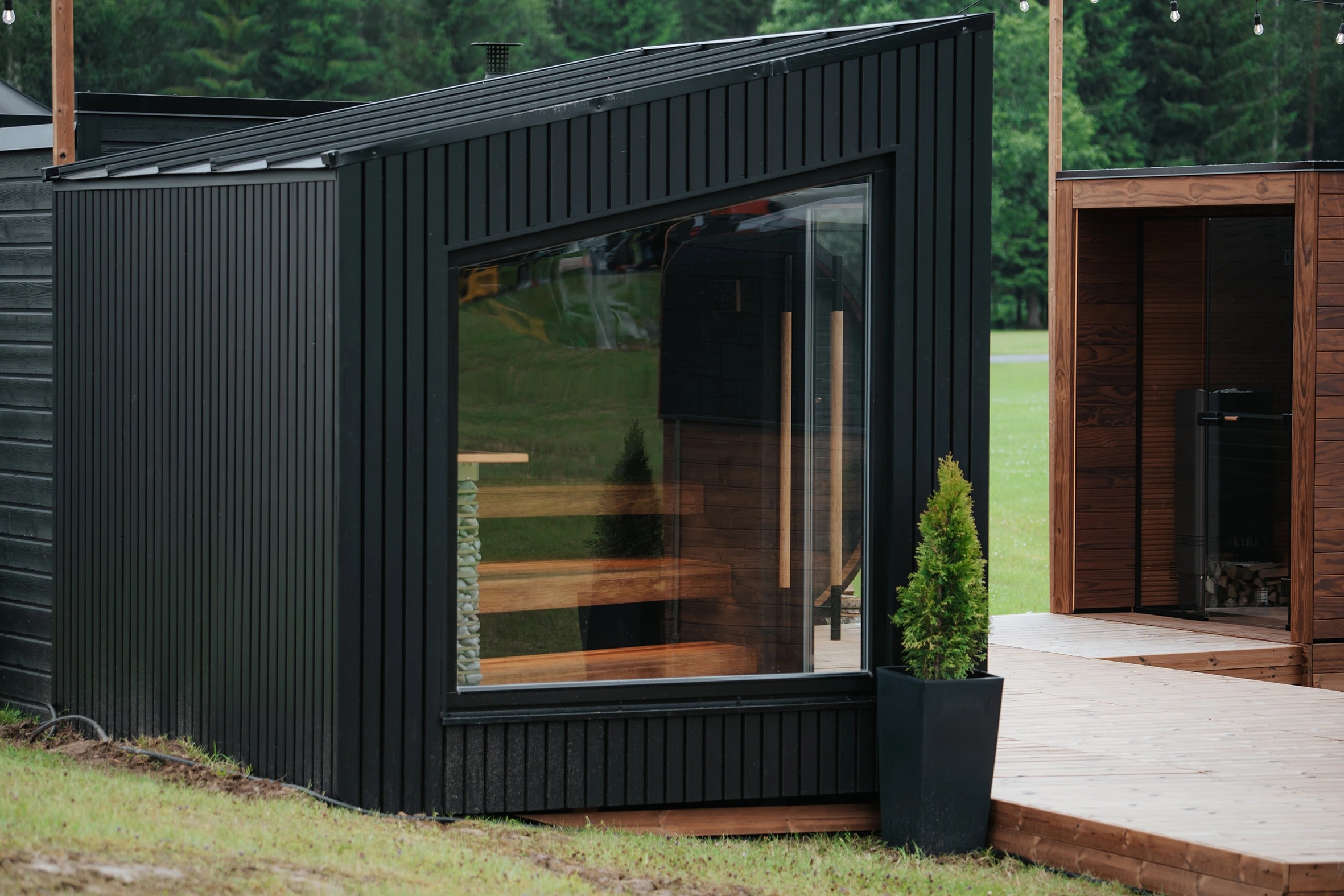 Dark-clad Terra outdoor sauna with a sloping roof and large glazed window